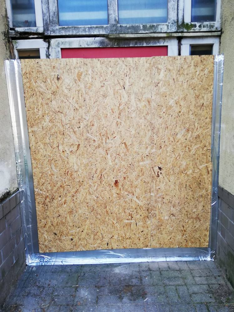 Nachher: Eingang mit Holzplatte verschlossen